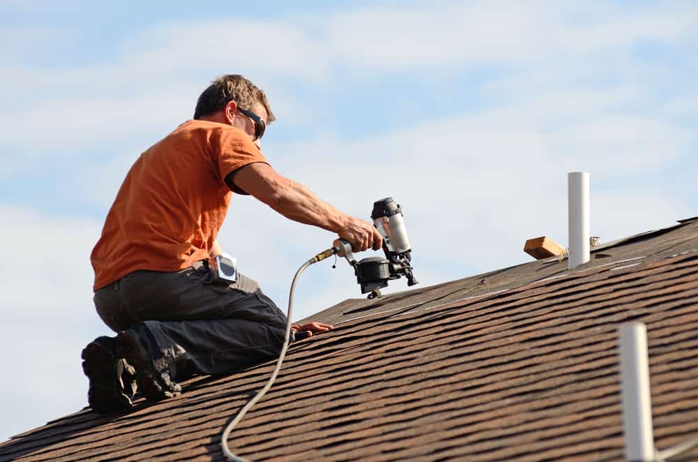 Building Contractor Putting The Asphalt Roofing On A Large Commercial Building