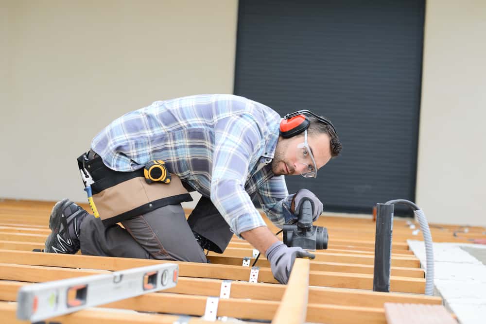 Handsome Young Man Carpenter Installing A Wood Floor Outdoor Terrace