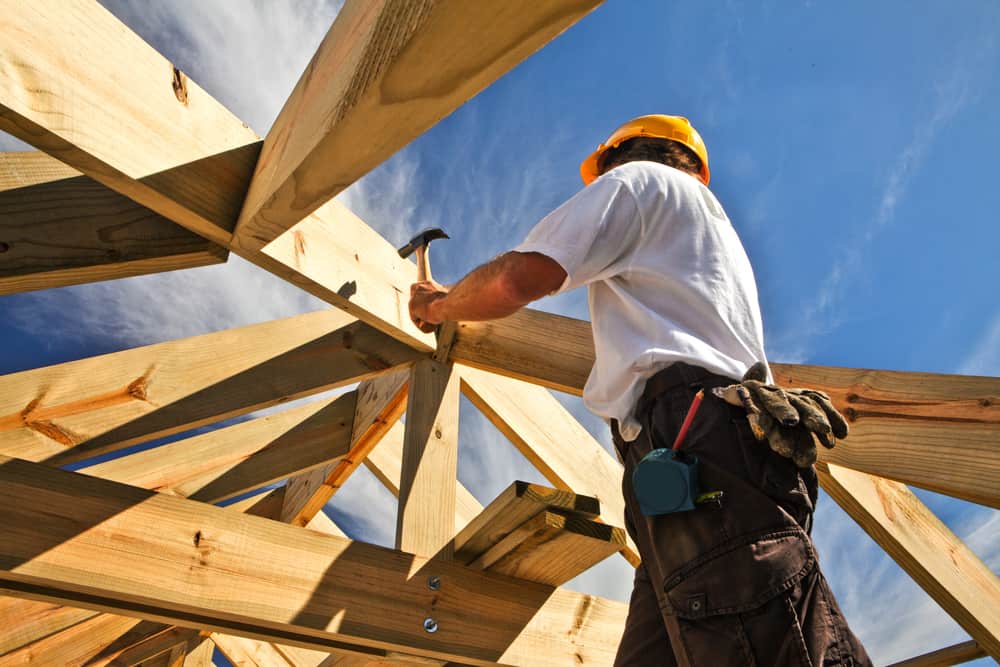 Carpenter Working On Roof Structure On Construction Site